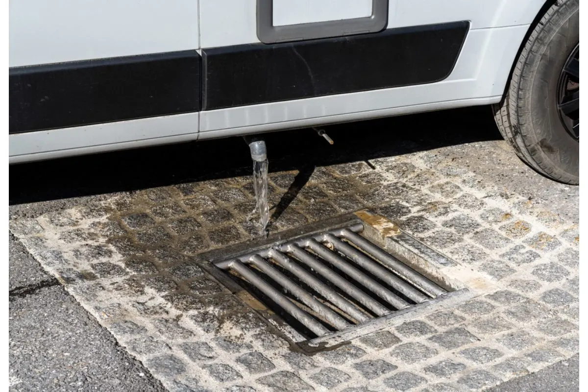 A RV is emptying it's water waster into the drainage so it can be refilled again.