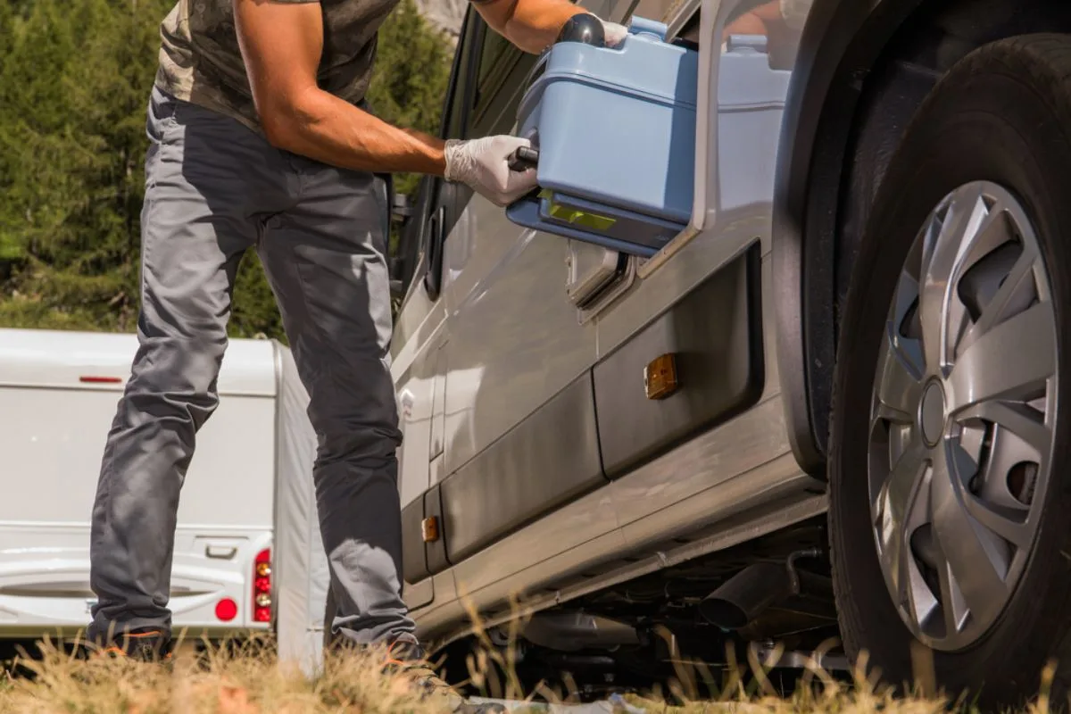 A man putting a water tank inside his RV for their necessaties while travelling.