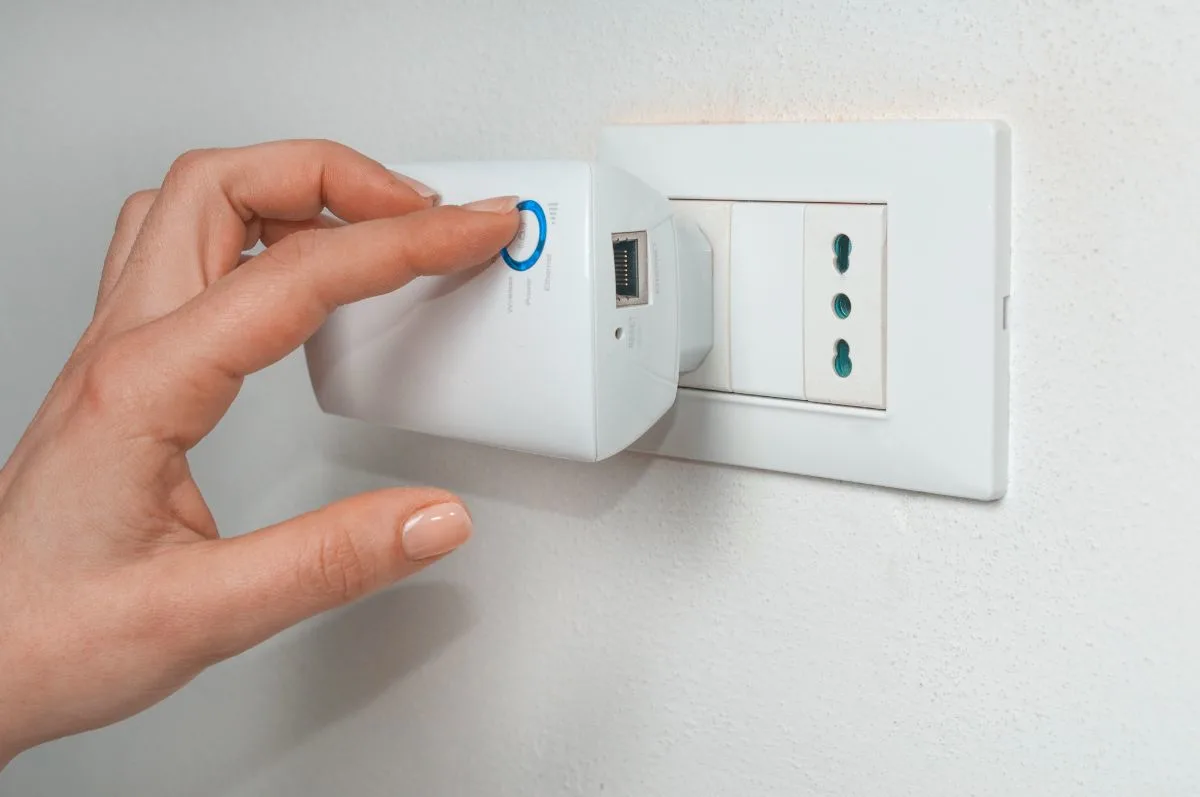 A woman turning on a Wifi repeater.