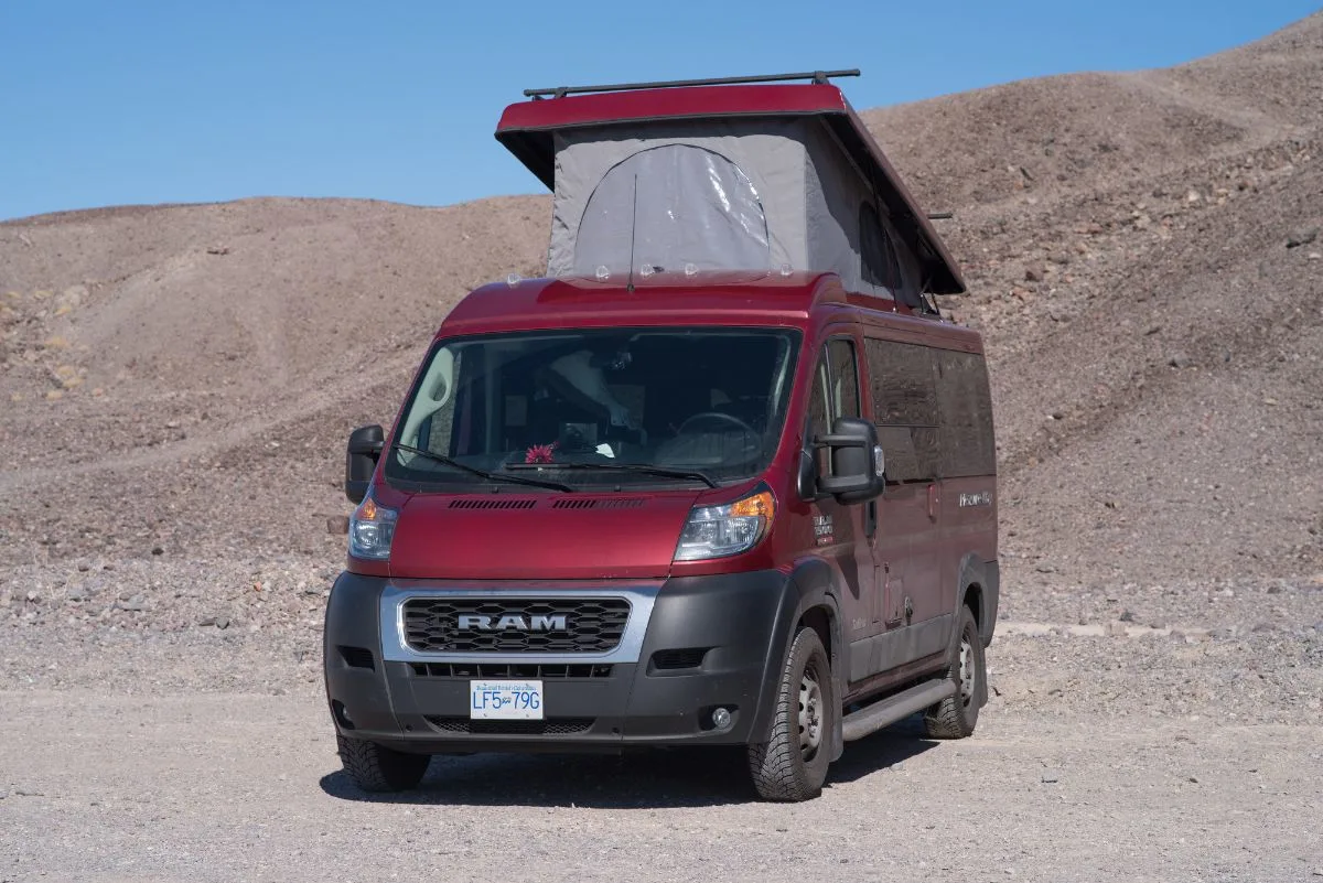 Maroon Coachmen Class B RV on camp site.