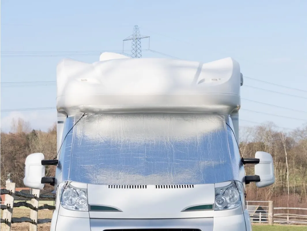 Front view of rv with a silver screen on its windscreen as protection from snow.