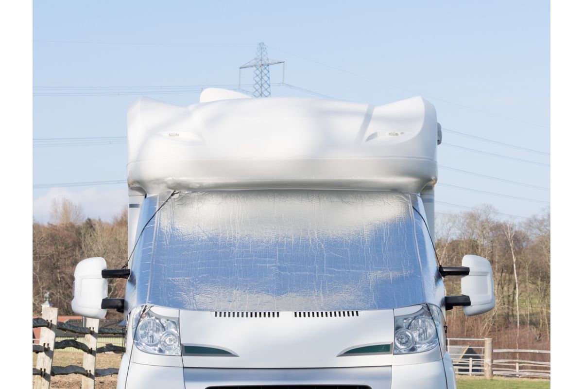 Front view of rv with a silver screen on its windscreen as protection from snow.