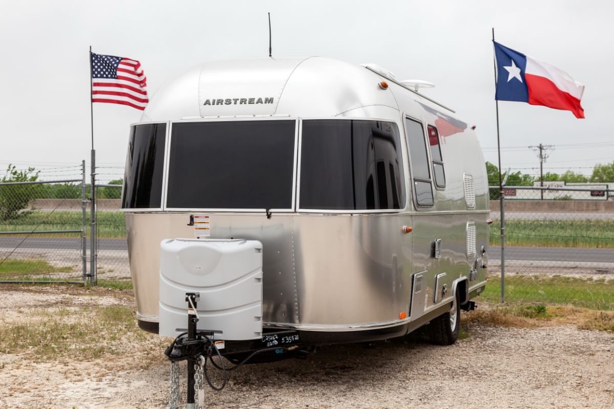 Front view of aluminum rv with two flags both side.