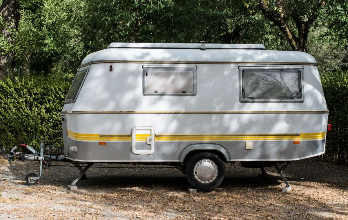 Side view of an old fiberglass rv in the campsite.