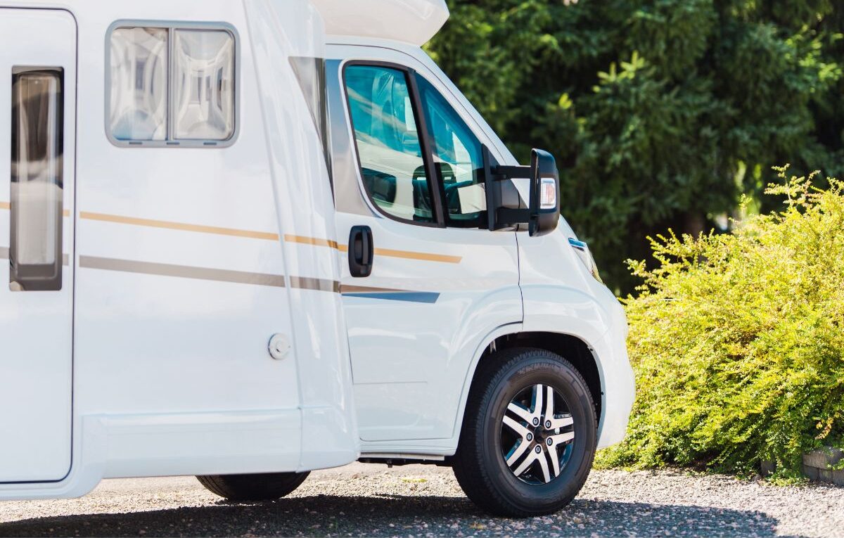 A white fiberglass rv siding parked in camping spot.