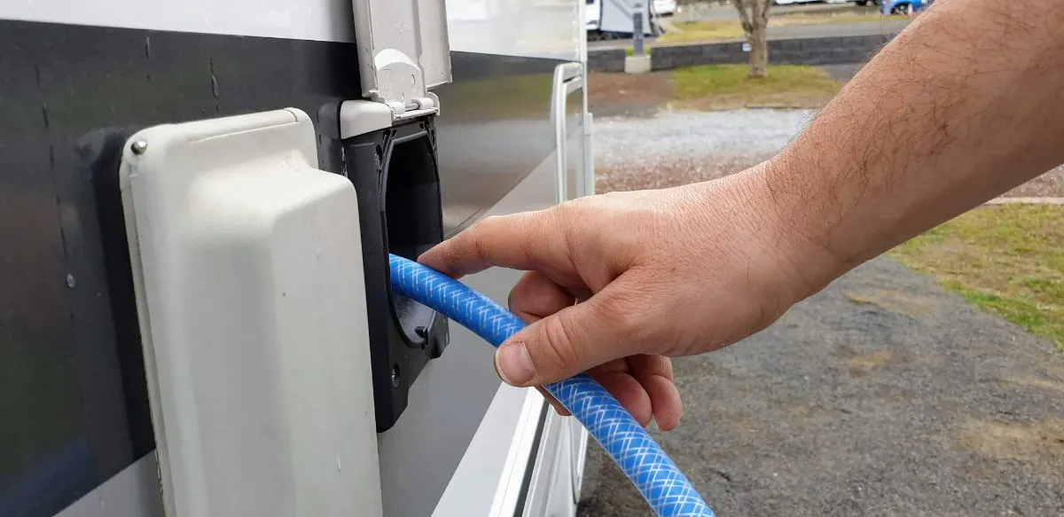 Man's hand refilling fresh water on fresh water tank.