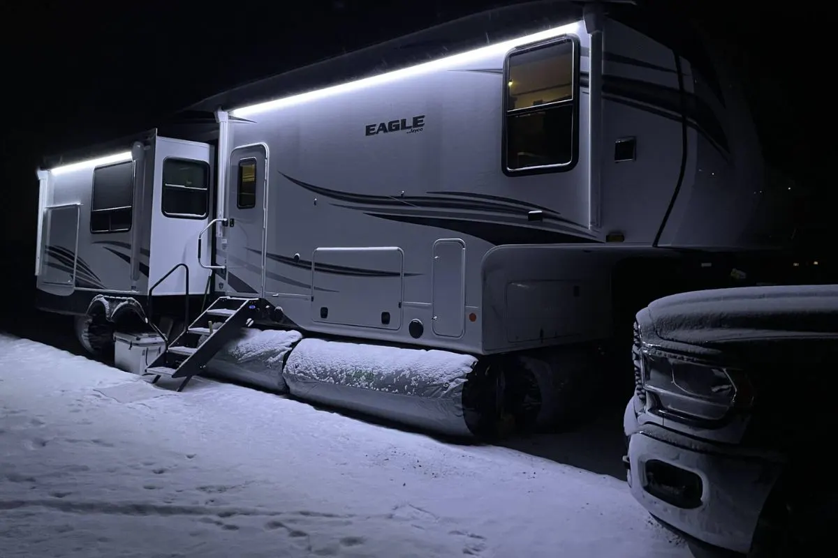 A RV or recreational van in the snow with inflatable RV skirt for protection.