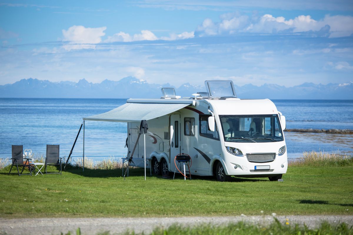 RV camper with awning on camp site near the sea.