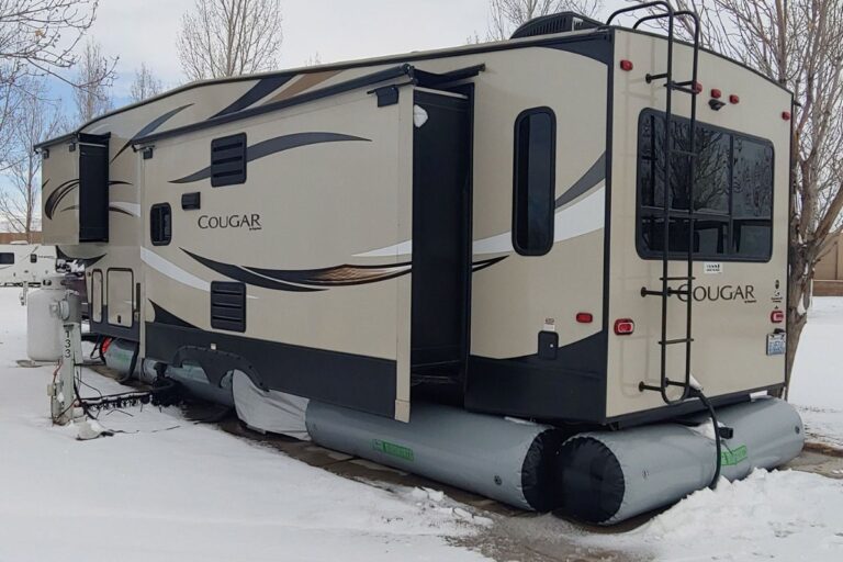 A RV or recreational van parked during winter with RV skirts to protect the van from the winter.