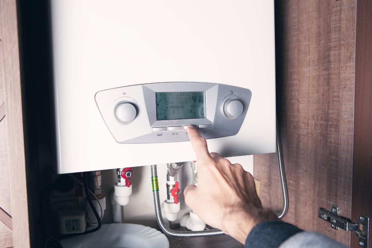 A man's hand pressing water heater button.