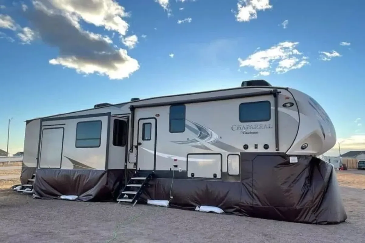 A white RV with a heavy duty vinyl skirt for protection during winter.