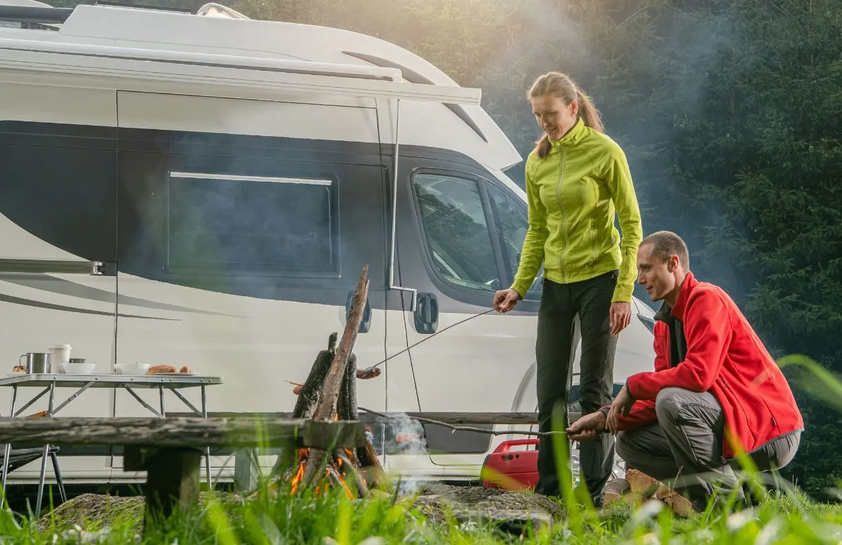 A couple grilling foods on camping near RV.