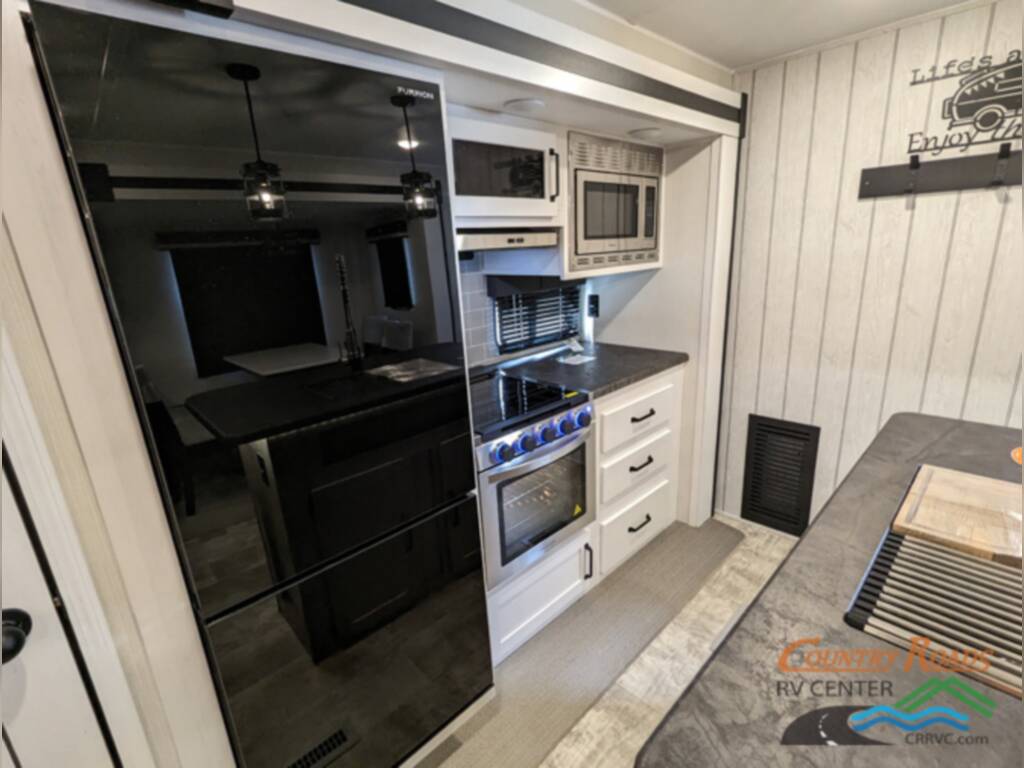 Kitchen with a fridge, gas burner, ovens, and drawers.