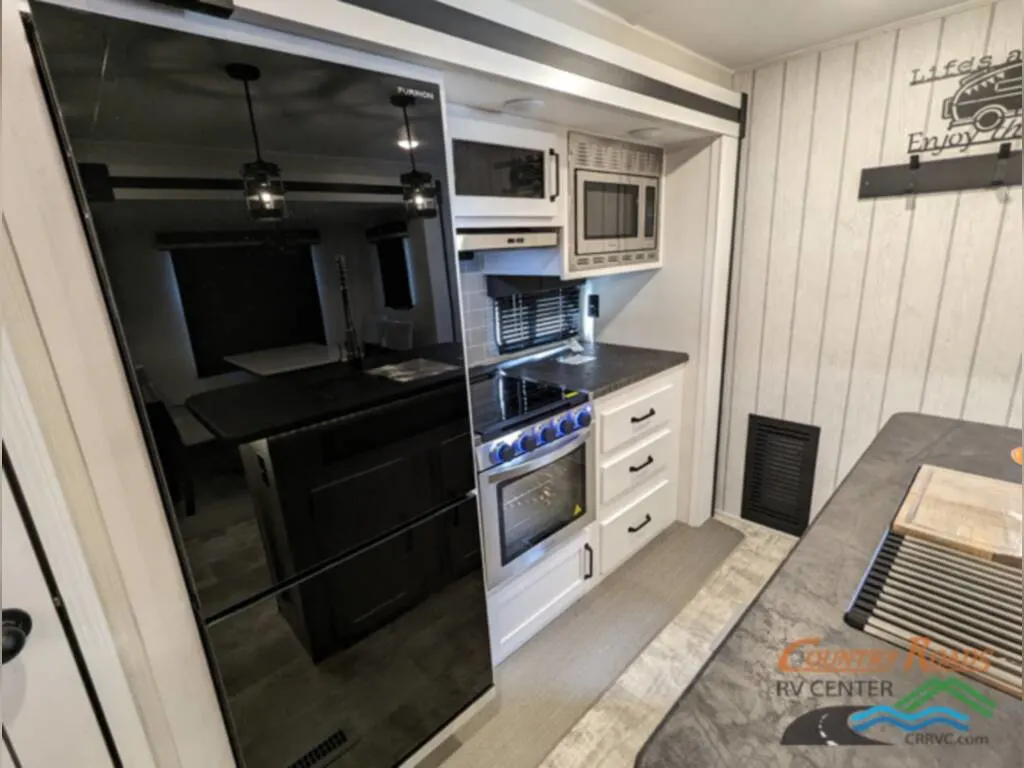 Kitchen with a fridge, gas burner, ovens, and drawers.