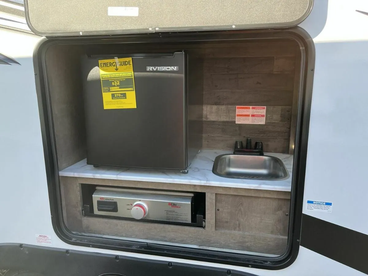 Outdoor kitchen with a gas burner and a fridge.