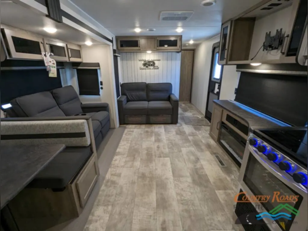 Interior of the New 2024 Palomino PUMA 30RKQS Travel Trailer RV with a dinette, living area and a kitchen.