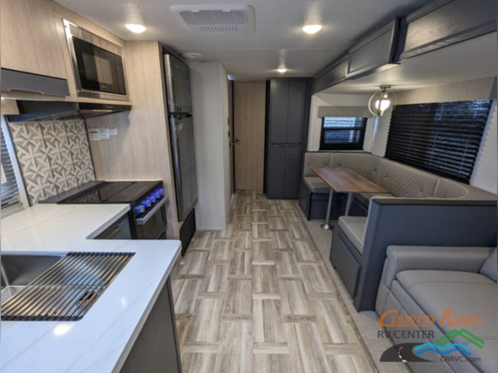 Interior of the New 2024 Prime Time TRACER 31BHD Travel Trailer RV with a dinette, kitchen and reclining chairs.