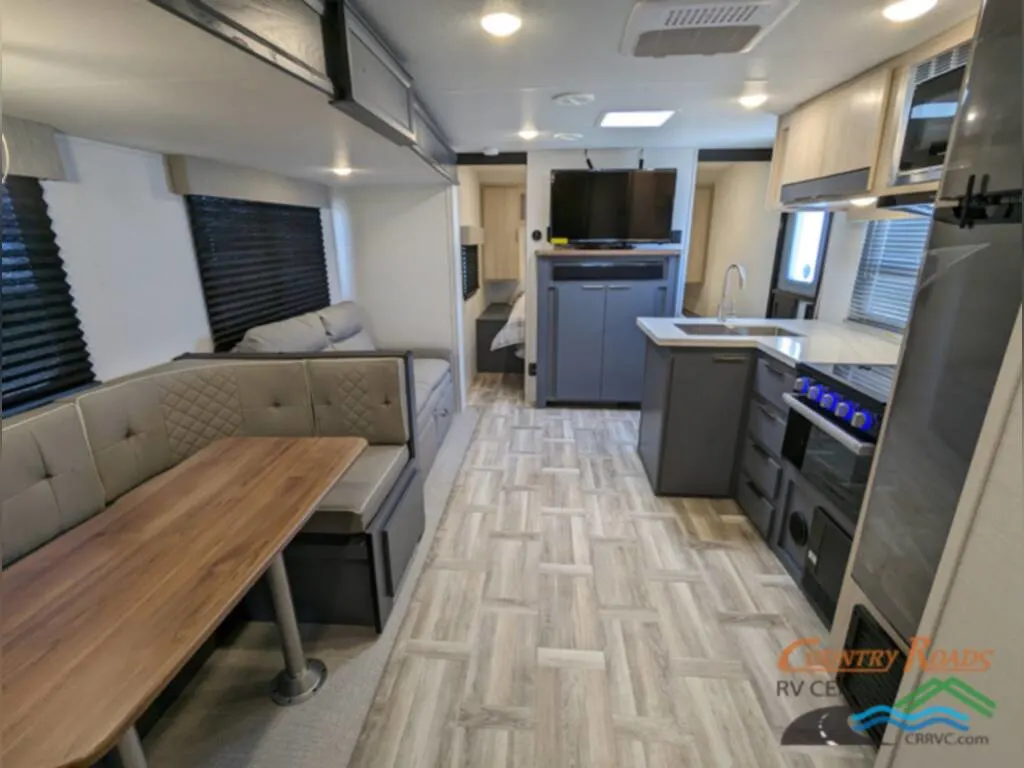 Interior of the New 2024 Prime Time TRACER 31BHD Travel Trailer RV with a dinette, kitchen and reclining chairs.