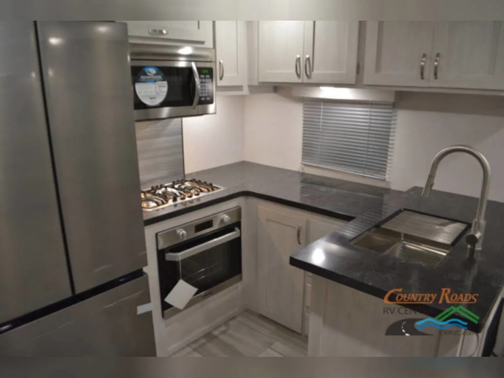 Kitchen with a gas burner, fridge, oven, sink and cabinets.