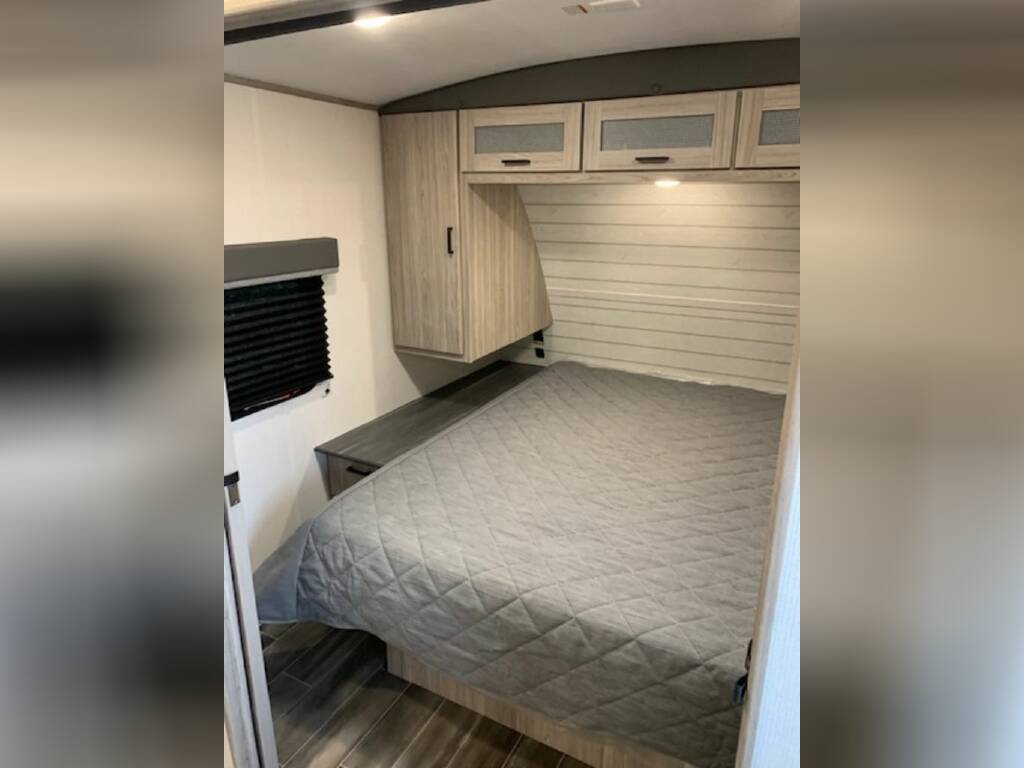 Bedroom with a queen size bed and overhead cabinets.