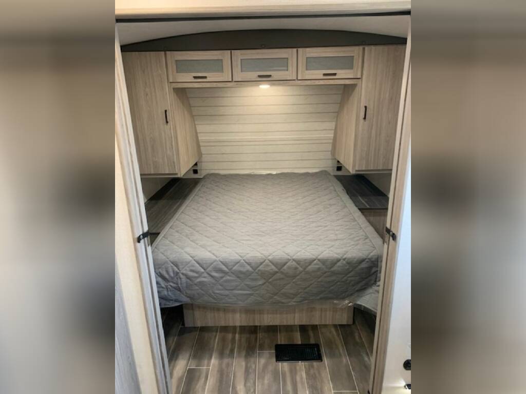 Bedroom with a queen size bed and overhead cabinets.