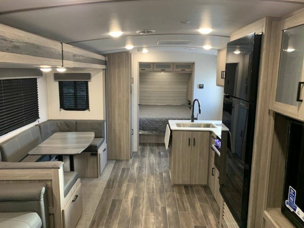 Interior view of the RV with a dinette, living area, bedroom and a kitchen.