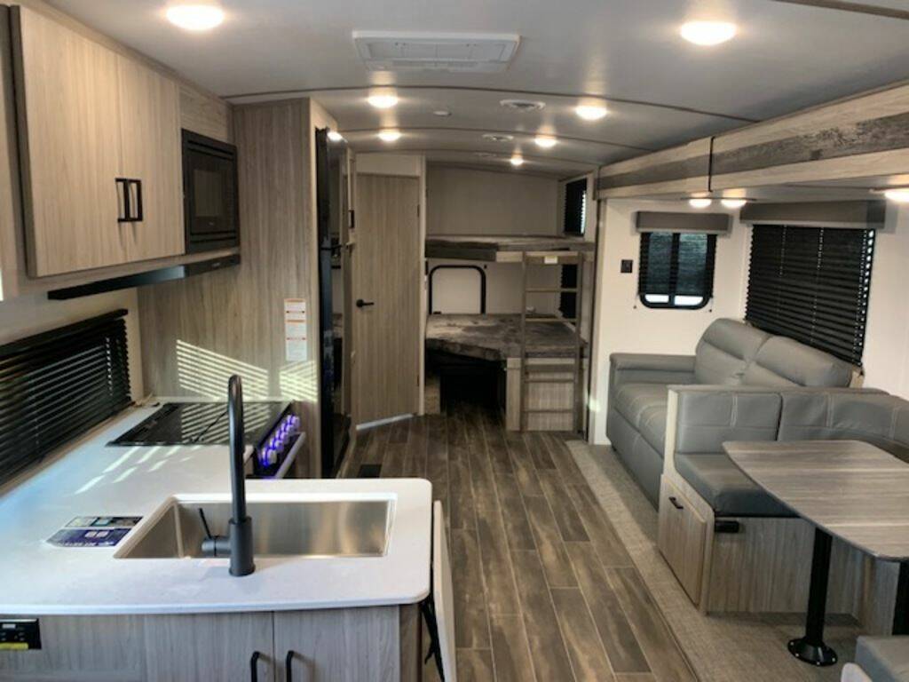 Interior view of the RV with a dinette, living area, bedroom and a kitchen.