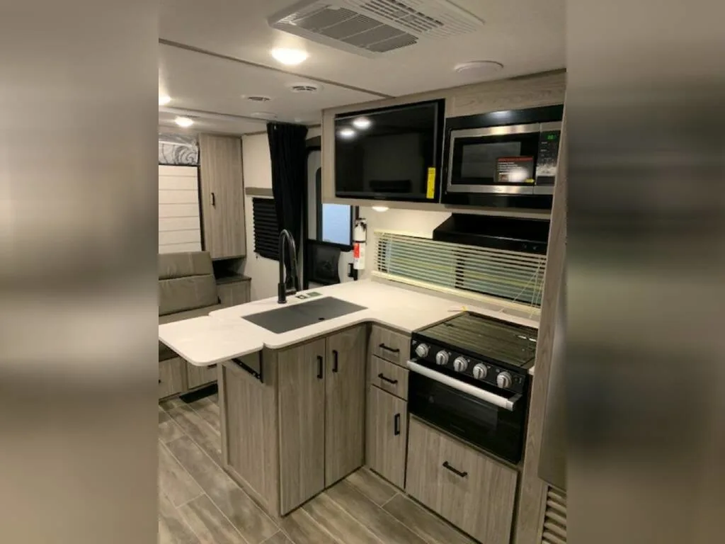 Kitchen with a gas burner, oven, sink and cabinets.