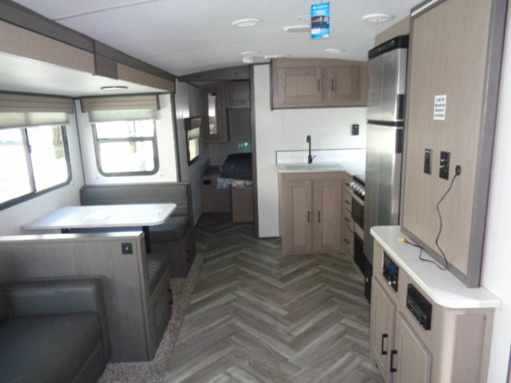 Interior view of the RV with a dinette, living space, bedroom and a kitchen.