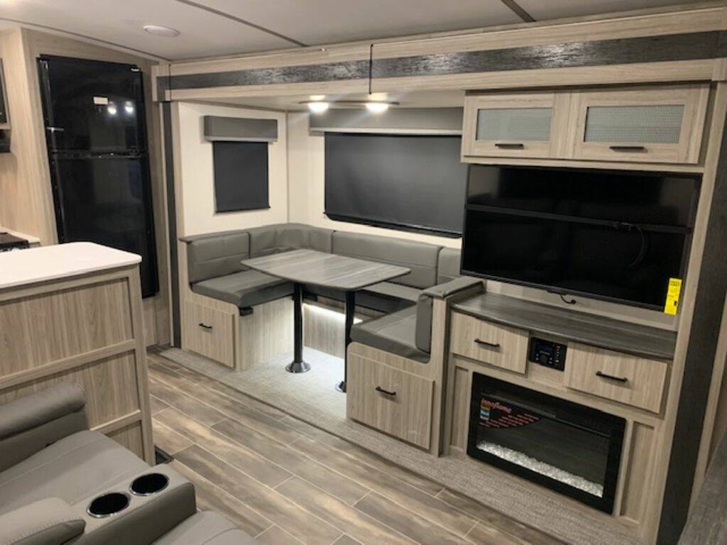 Interior view of the RV with a dinette, living area and an entertainment center.