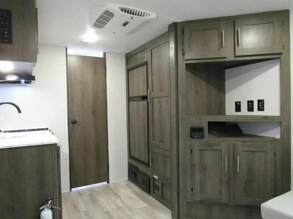 Interior view of the RV with an entertainment center and a kitchen.