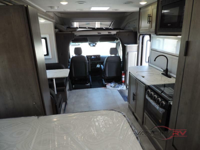 Interior view of the RV with a bedroom, dinette, kitchen and driver's seat.