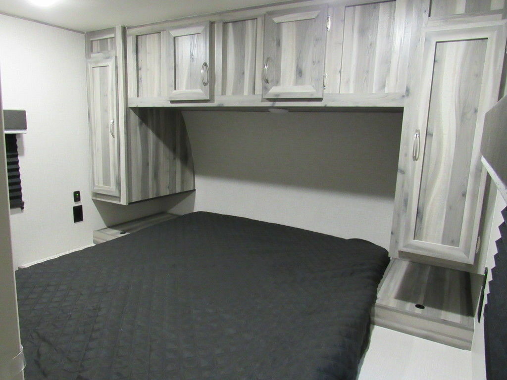 Bedroom with a queen size bed, overhead cabinets and a shirt closet.