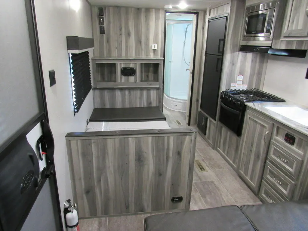 Interior view of the RV with a dinette, bathroom and a kitchen.