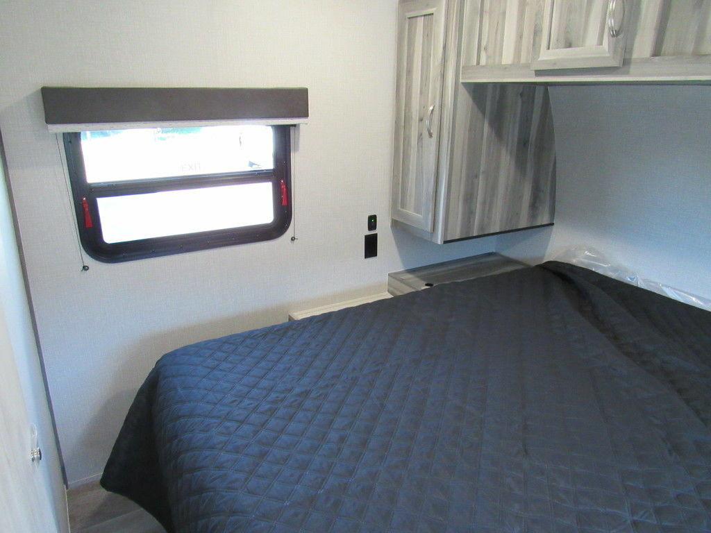 Bedroom with a queen size bed, overhead shelf and a shirt closet.