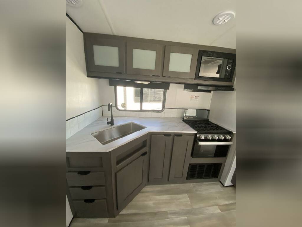 Kitchen with a gas burner, oven, sink and cabinets.