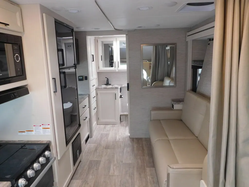 Interior view of the RV with a living space, bathroom and a kitchen.