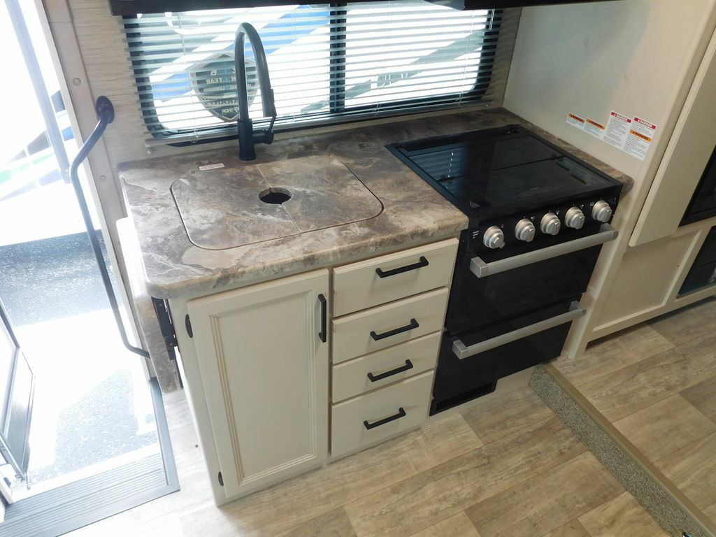 Kitchen with a gas burner, sink, drawers and cabinets.