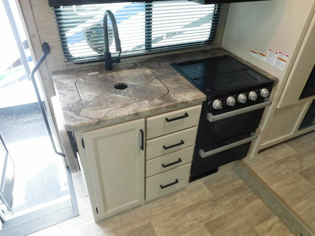 Kitchen with a gas burner, sink, drawers and cabinets.