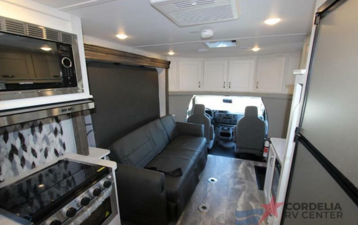 Interior view of the RV with a living space, a kitchen, and driver's seat.