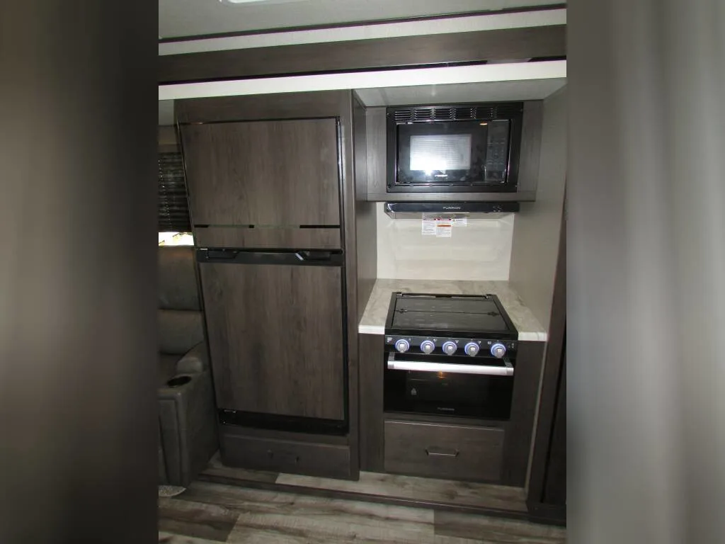 Kitchen with a gas burner, fridge, oven, and drawers.