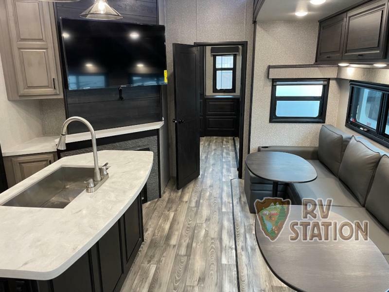 Interior view of the RV with a dinette, entertainment center and a kitchen sink.