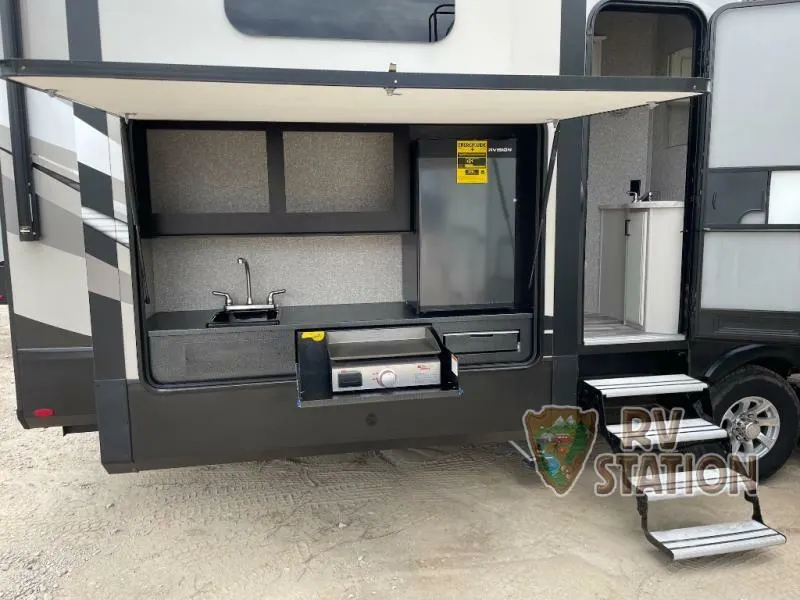 Outdoor kitchen with a gas burner, fridge and a sink.