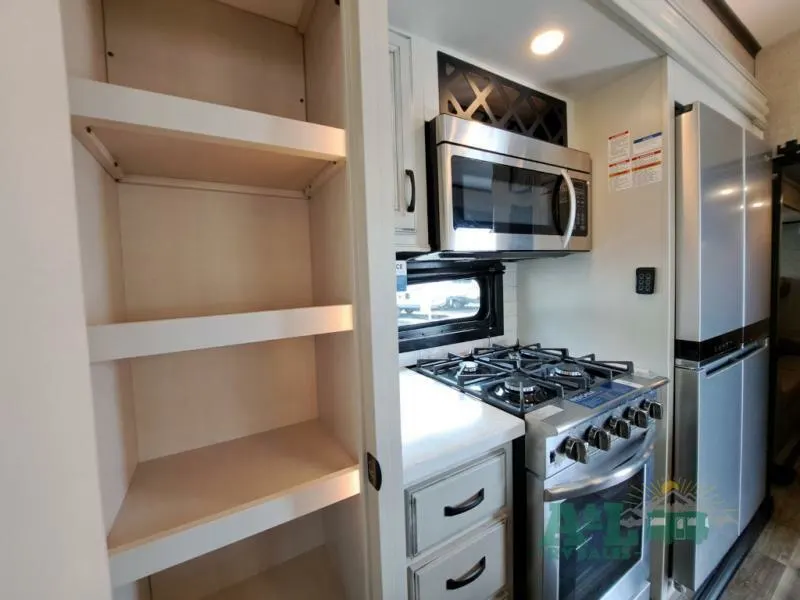 Kitchen with a gas burner, fridge, oven, and shelves.