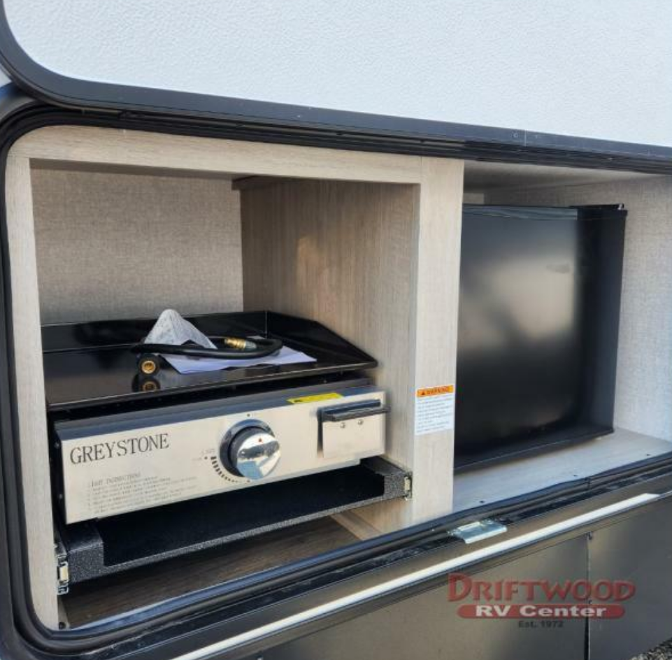 Outdoor kitchen with a gas burner and a fridge.