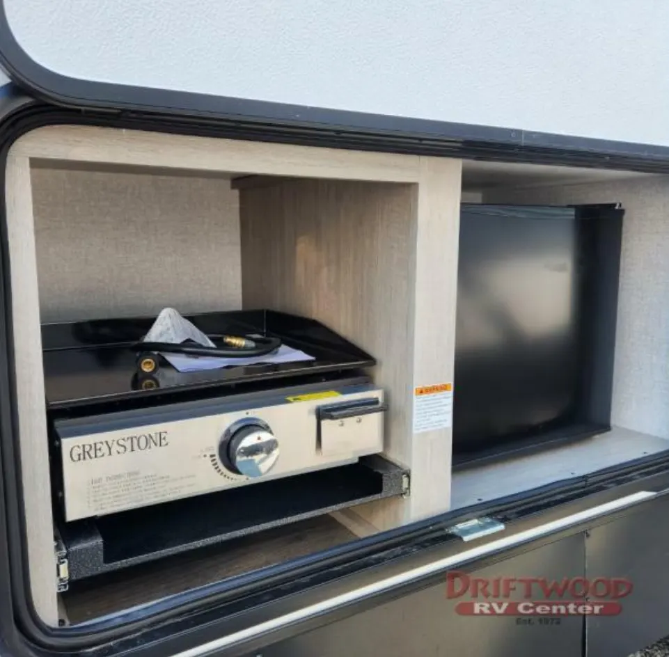 Outdoor kitchen with a gas burner and a fridge.