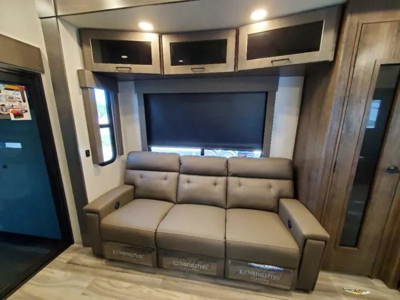 Living space with leather seats and overhead cabinets.