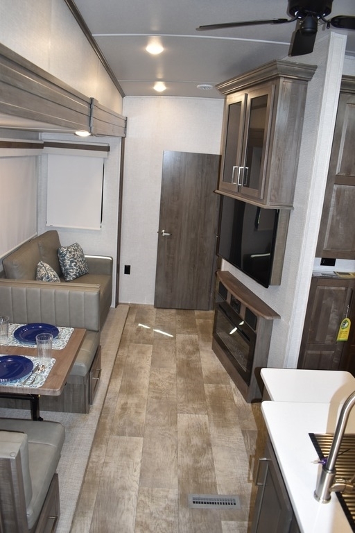 Interior view of the RV with a dinette, living space, entertainment center and a kitchen.