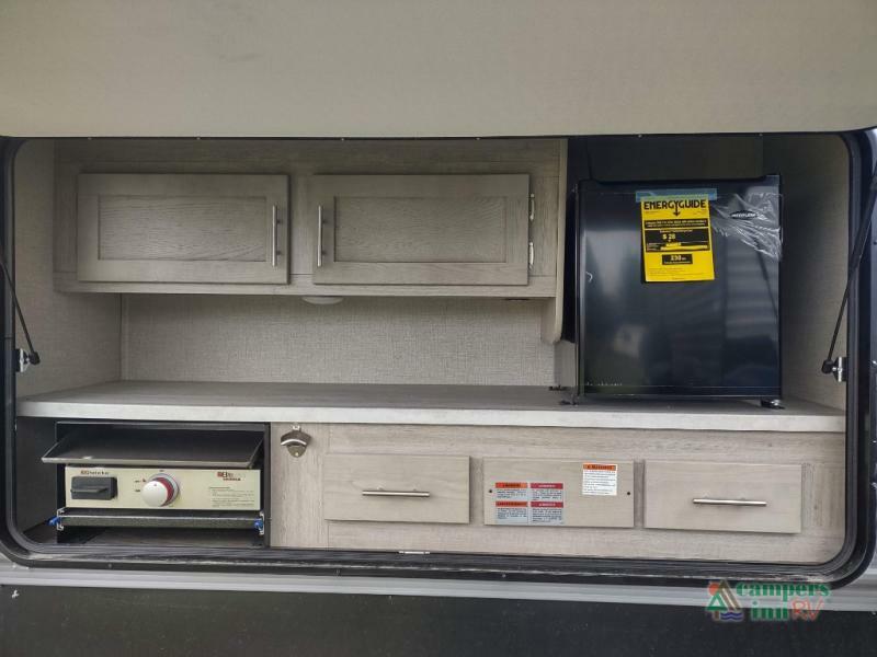 Outdoor kitchen with a gas burner, cabinets and a fridge.