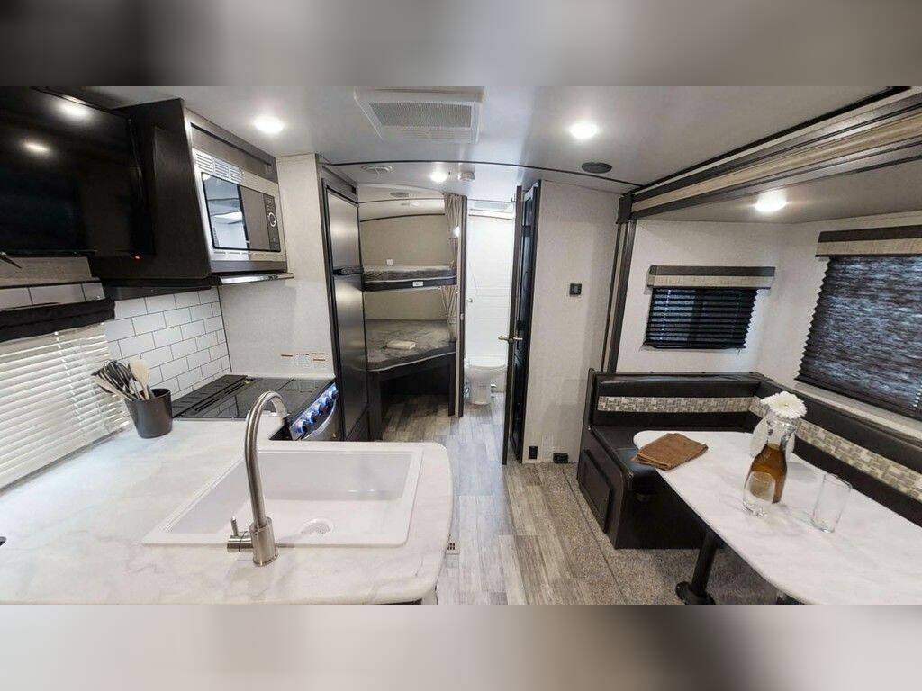 Interior view of the RV with a dinette, bathroom and a kitchen.